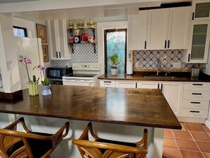 A kitchen with a central island, white cabinets, a microwave, and a stove. - Charming guest house in Antique Row district (West Palm Beach)