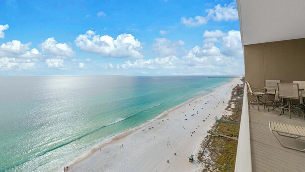 A beach view from a balcony with outdoor seating.
