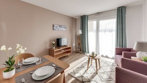 A modern living room with a dining area, a television, and a sofa. - Zenao Appart'hôtels Challans (Challans)