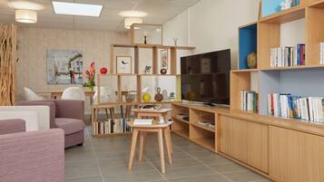 Una sala moderna con un sofá, una mesa de centro, un televisor y estanterías de madera con libros.