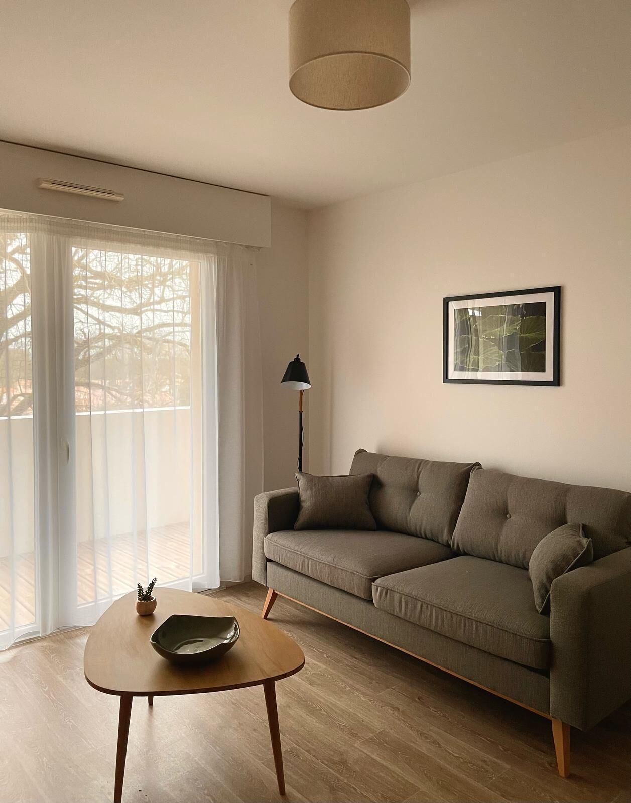 A living room with a sofa, a table, a lamp, and a framed picture on the wall.