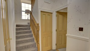 A staircase with carpeted steps and wooden handrails, leading to a door with a light switch on the wall. - The Clachan Wick in Wick (Wick)