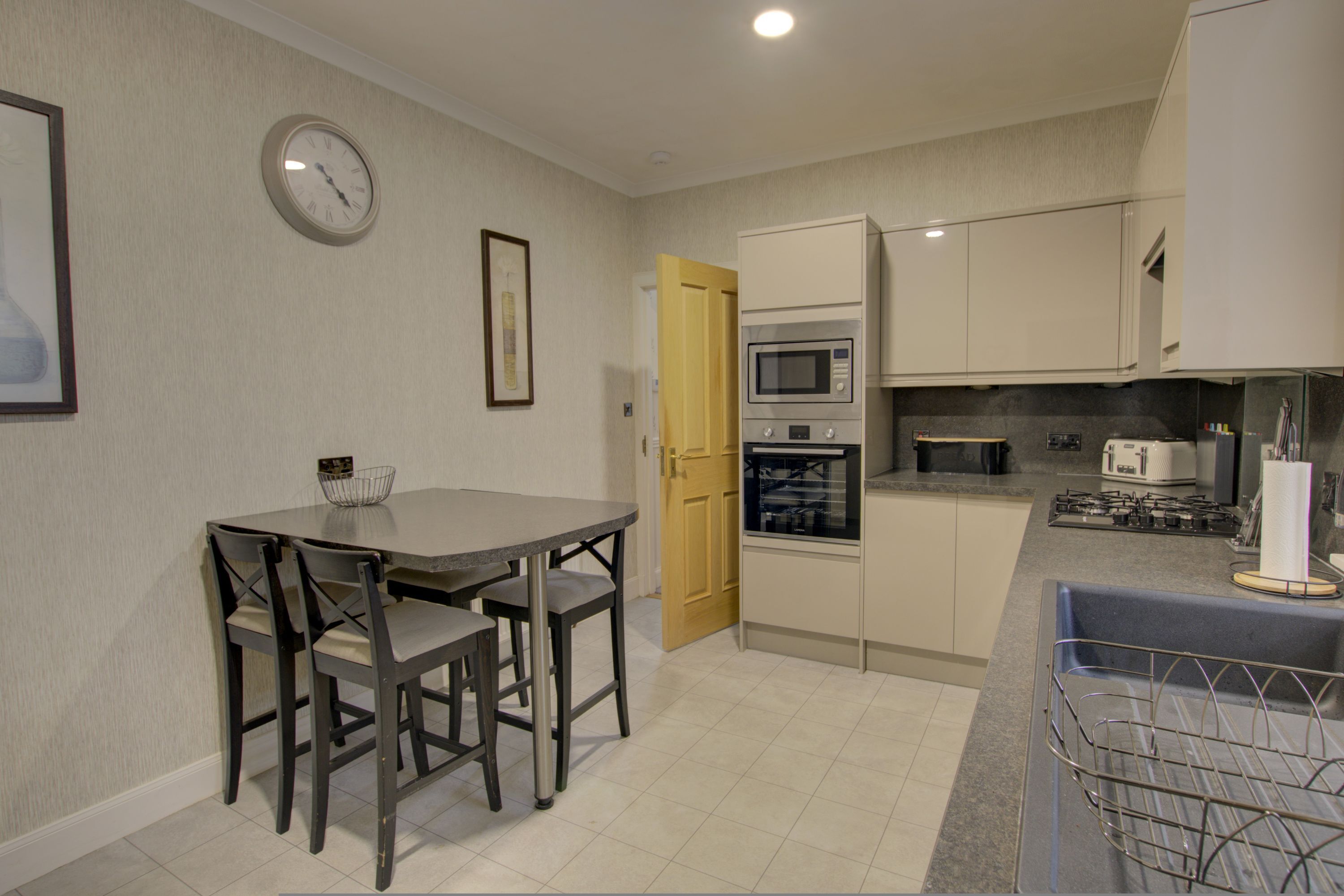 A compact kitchen with a dining table, chairs, a microwave, oven, and a sink.