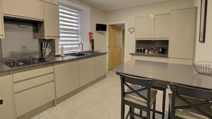 A modern kitchen with a gas stove, sink, and a dining area with chairs.