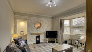 A living room with a sofa, a coffee table, a TV, and a fireplace. - The Clachan Wick in Wick (Wick)