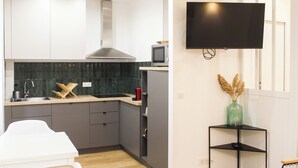 Eine moderne Küche mit grauen Schränken, einer Edelstahl-Dunstabzugshaube, einer Mikrowelle und einem an der Wand befestigten Fernseher.