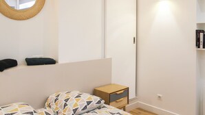 Ein Schlafzimmer mit einem Bett, einem Nachttisch, einem Spiegel, einem Kleiderschrank und einem Regal mit Büchern.