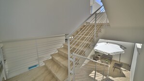 A staircase with white railings leading to a balcony with a table and chairs. - Riviera Luxury Rooms (Porto Cesareo)