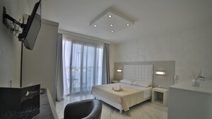 A modern hotel room with a bed, bedside tables, a desk, and a chair. - Riviera Luxury Rooms (Porto Cesareo)
