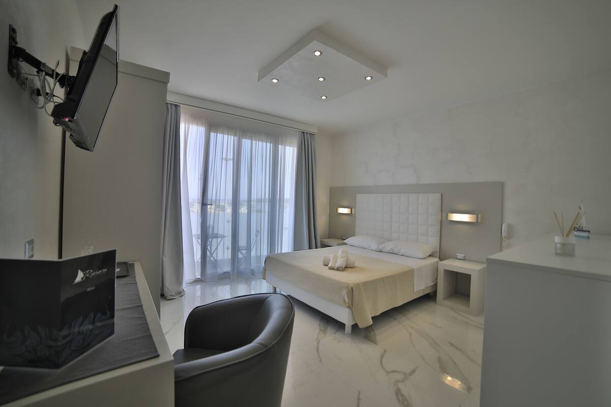 A modern hotel room with a bed, bedside tables, a desk, and a chair.