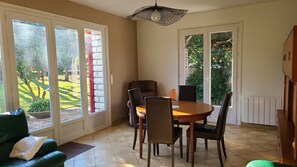 Un comedor con mesa y sillas, ventanas amplias y vistas a un jardín.