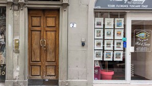 Un edificio con una puerta doble de madera y un escaparate que muestra cuadros enmarcados.