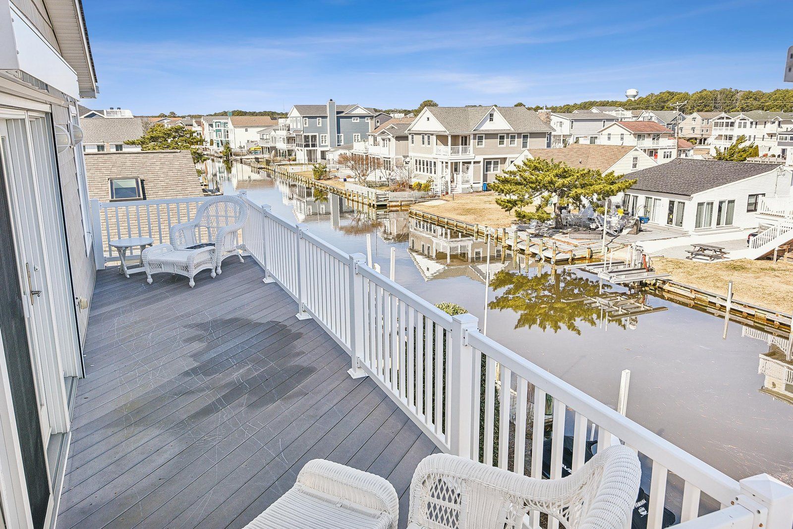 A residential area with houses, a dock, and a wooden deck with chairs.