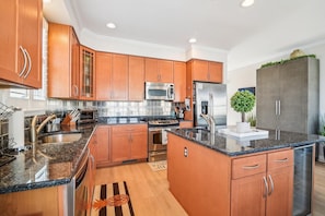 A modern kitchen with wooden cabinets, stainless steel appliances, and a granite countertop. - Bethany Beach Waterfront Oasis! (South Bethany)