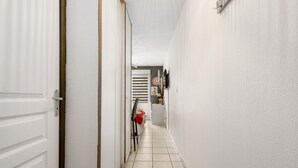 A narrow hallway with white walls and a tiled floor. - Le Flamboyant du Fonserane - Climatisé (Béziers)