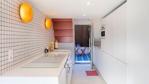 Una cucina moderna con mobili bianchi, uno schienale piastrellato e un piano in vetro.