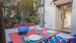 Un tavolo da pranzo all'aperto con sedie, una ciotola blu e piatti.
