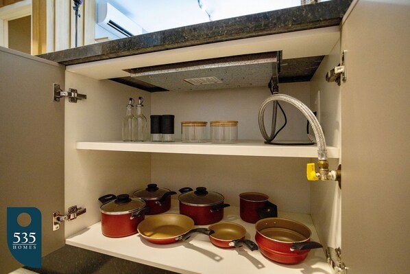 A kitchen with pots and pans on shelves, a faucet, and a water heater.