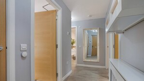 Un pasillo con una puerta de madera, un interruptor de luz y un espejo en la pared.