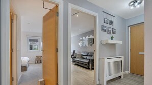 Una sala de estar moderna con un sofá gris, un radiador blanco y un estante con fotografías.