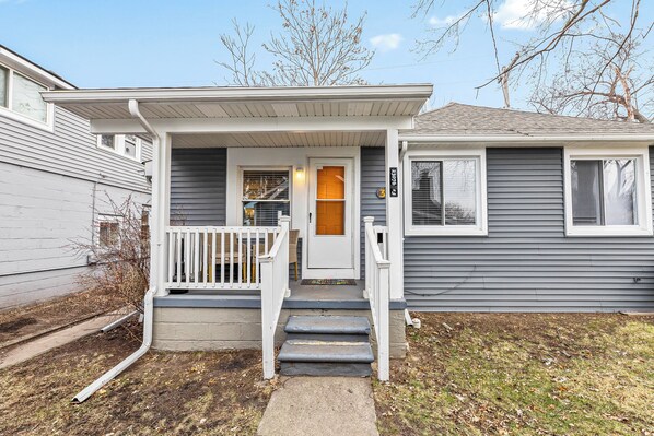 A two-story house with a front porch, a small staircase, and a front door. - Cozy 1-bedroom apartment with WiFi, AC in charming Hazel Park (Hazel Park)