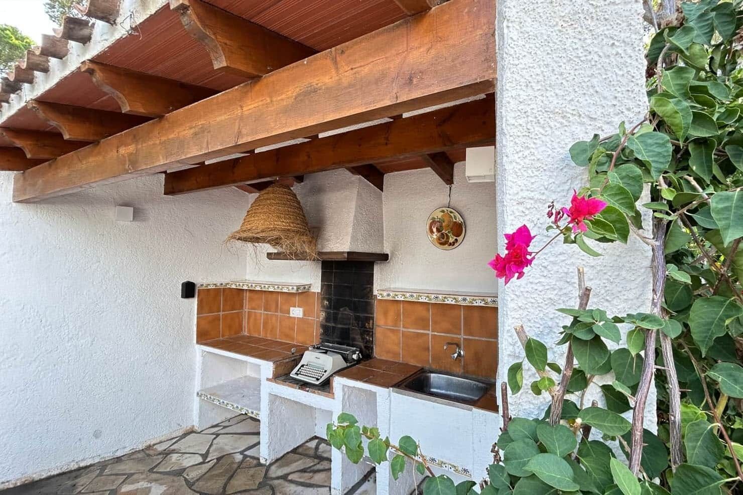 A rustic outdoor kitchen with a chimney, a sink, and a decorative plate on the wall.