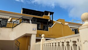 A yellow building with a balcony, a staircase, and a gate.
