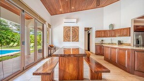 A modern kitchen with a large wooden island, built-in cabinets, and a view of a swimming pool. - Spectacular 4BR/4BA Villa with Private Pool & Parking WiFi, AC (Hacienda Pinilla)