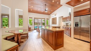 A spacious kitchen with wooden cabinets, a large island, and a built-in refrigerator. - Spectacular 4BR/4BA Villa with Private Pool & Parking WiFi, AC (Hacienda Pinilla)