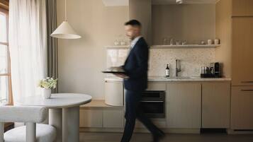A modern kitchen with a round dining table, a hanging light fixture, and a built-in oven.