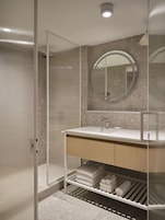 A modern bathroom with a glass shower enclosure, a sink with a mirror, and a towel rack.