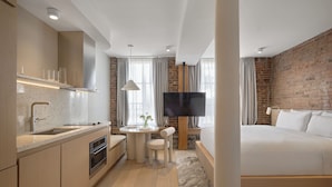 A modern hotel room with a kitchen, a dining area, and a large bed. - Corner Apartments  (Montréal)