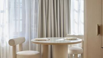 A modern dining area with a round table, four chairs, and a hanging light fixture.