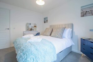 Une chambre à coucher comprenant un lit, une commode, un miroir et un tableau accroché au mur.
