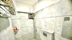Un baño con inodoro, bidé y lavabo. Hay un perchero y una repisa con artículos de aseo.