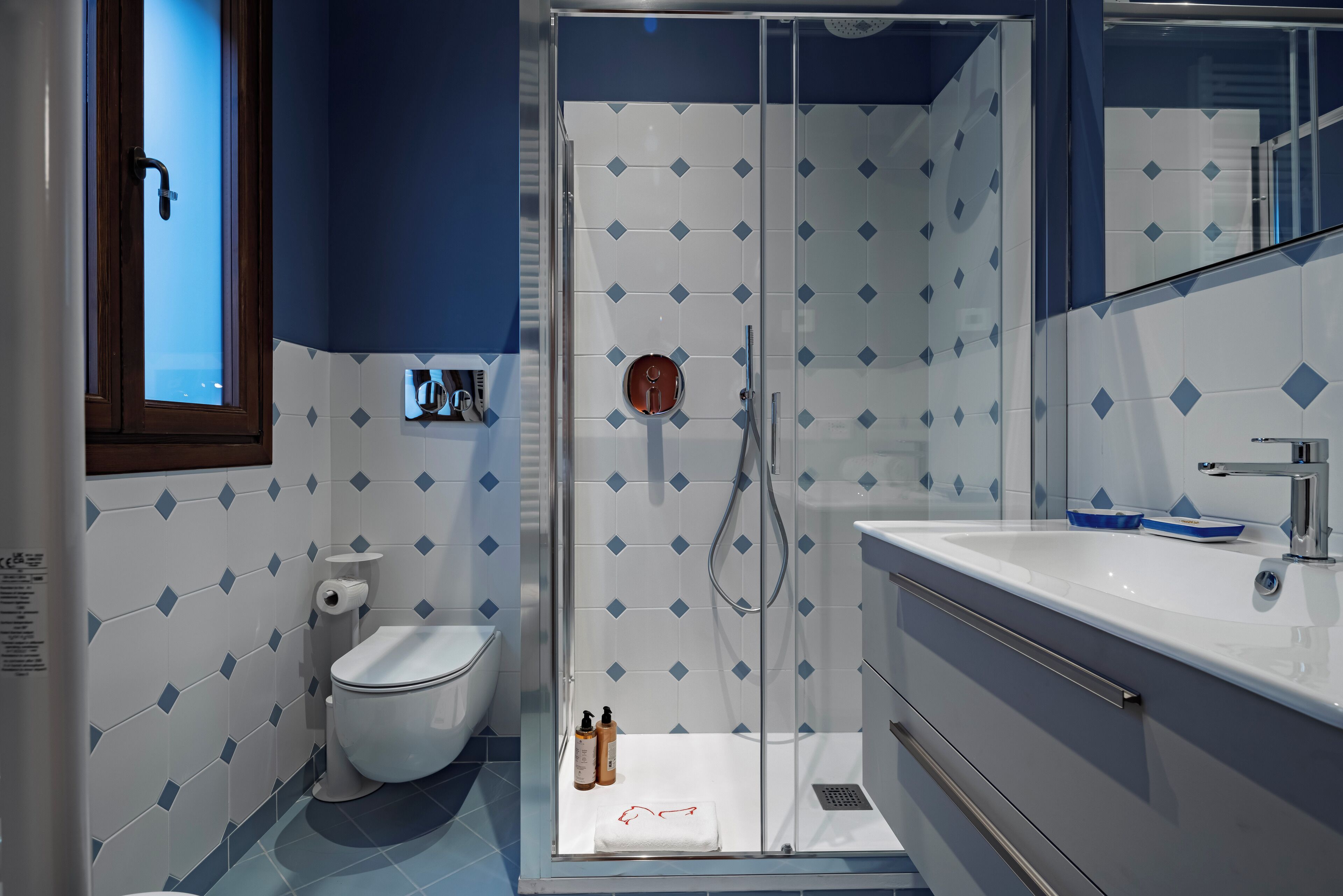 Een moderne badkamer met een douchecabine van glas, een witte wastafel en een toilet.