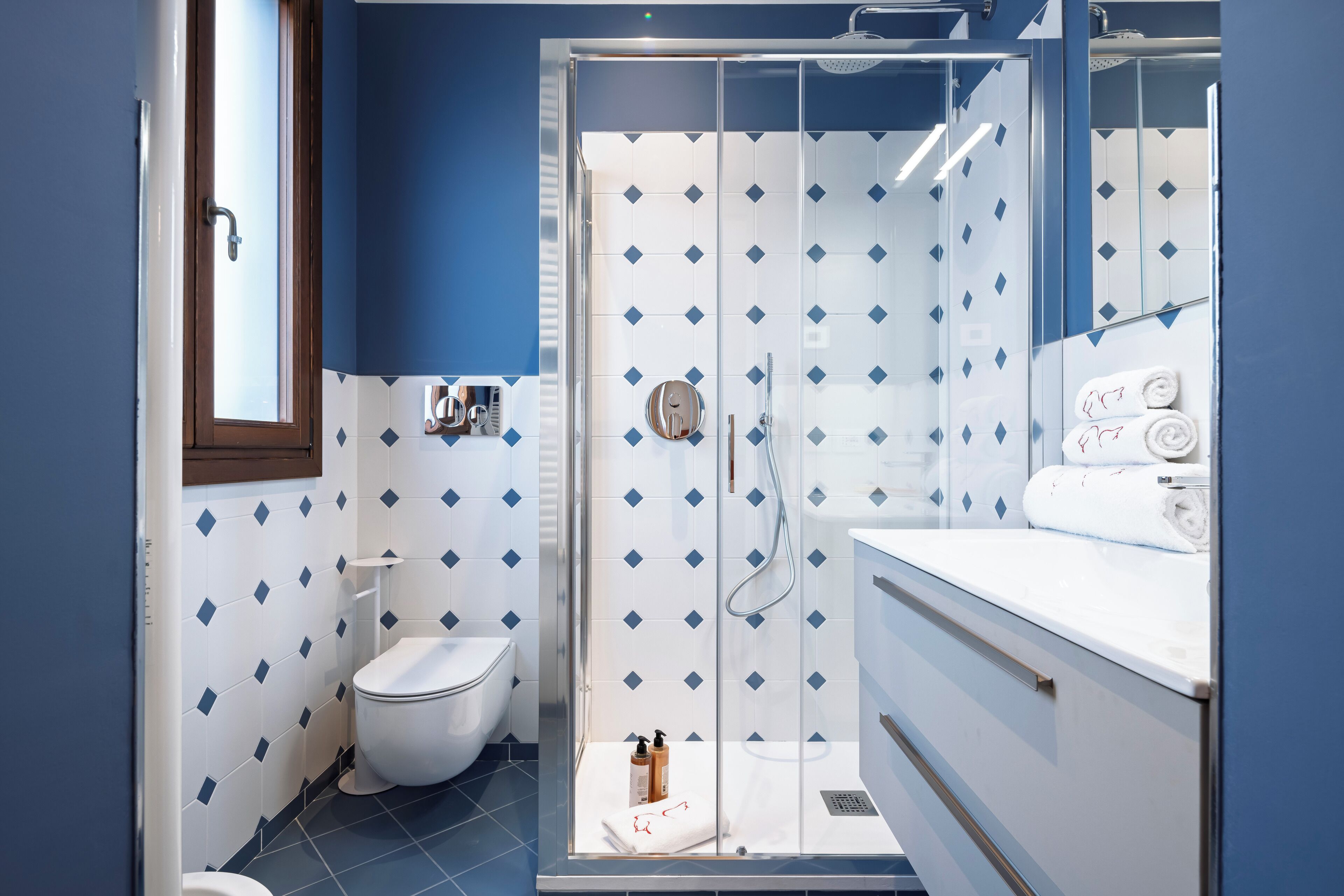 Un baño con ducha envuelta en vidrio, inodoro y lavabo con espejo.