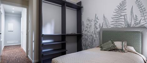 A bedroom with a bed, a wardrobe, and a wall with a botanical mural.