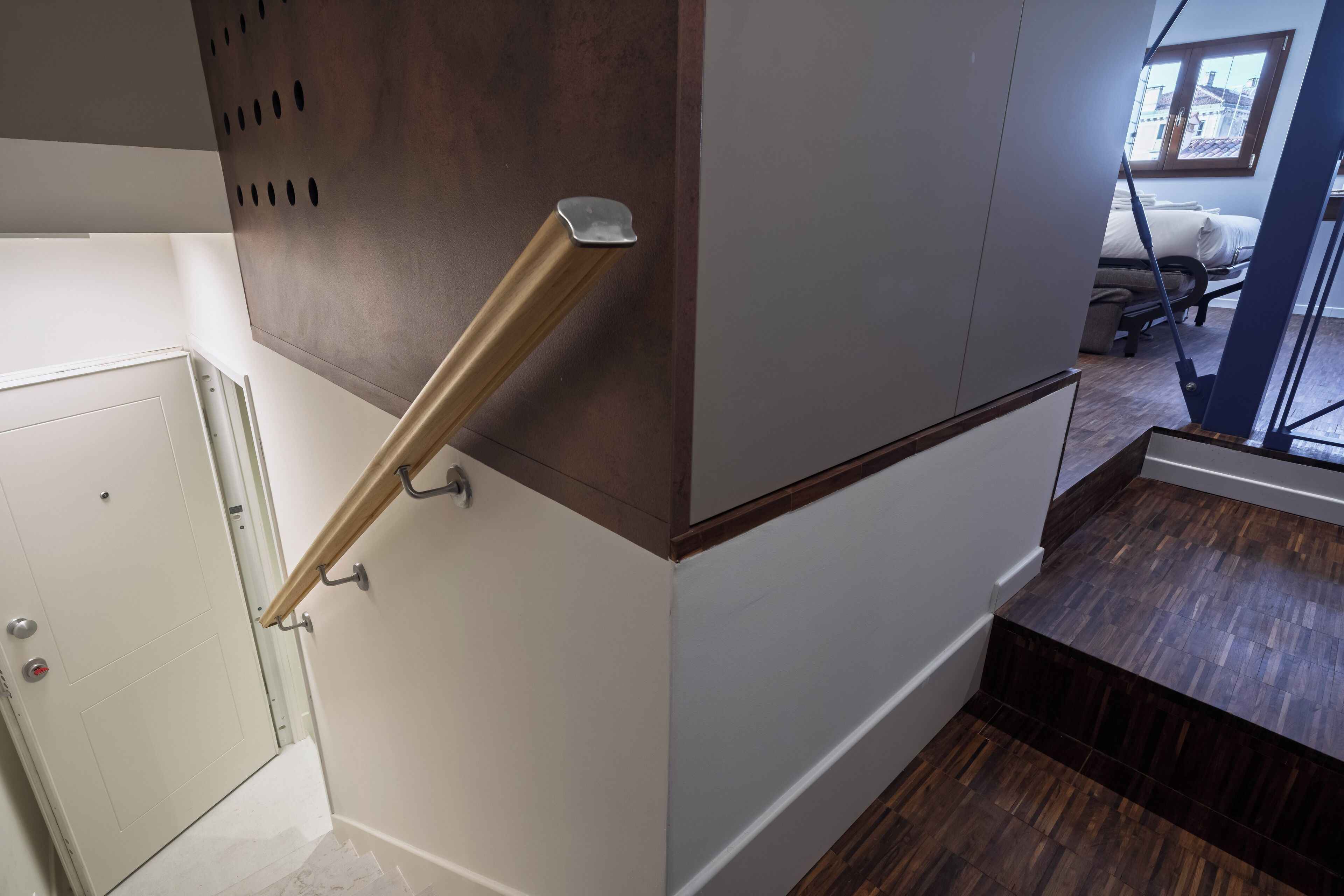Una escalera con barandilla de madera y una puerta blanca al final.