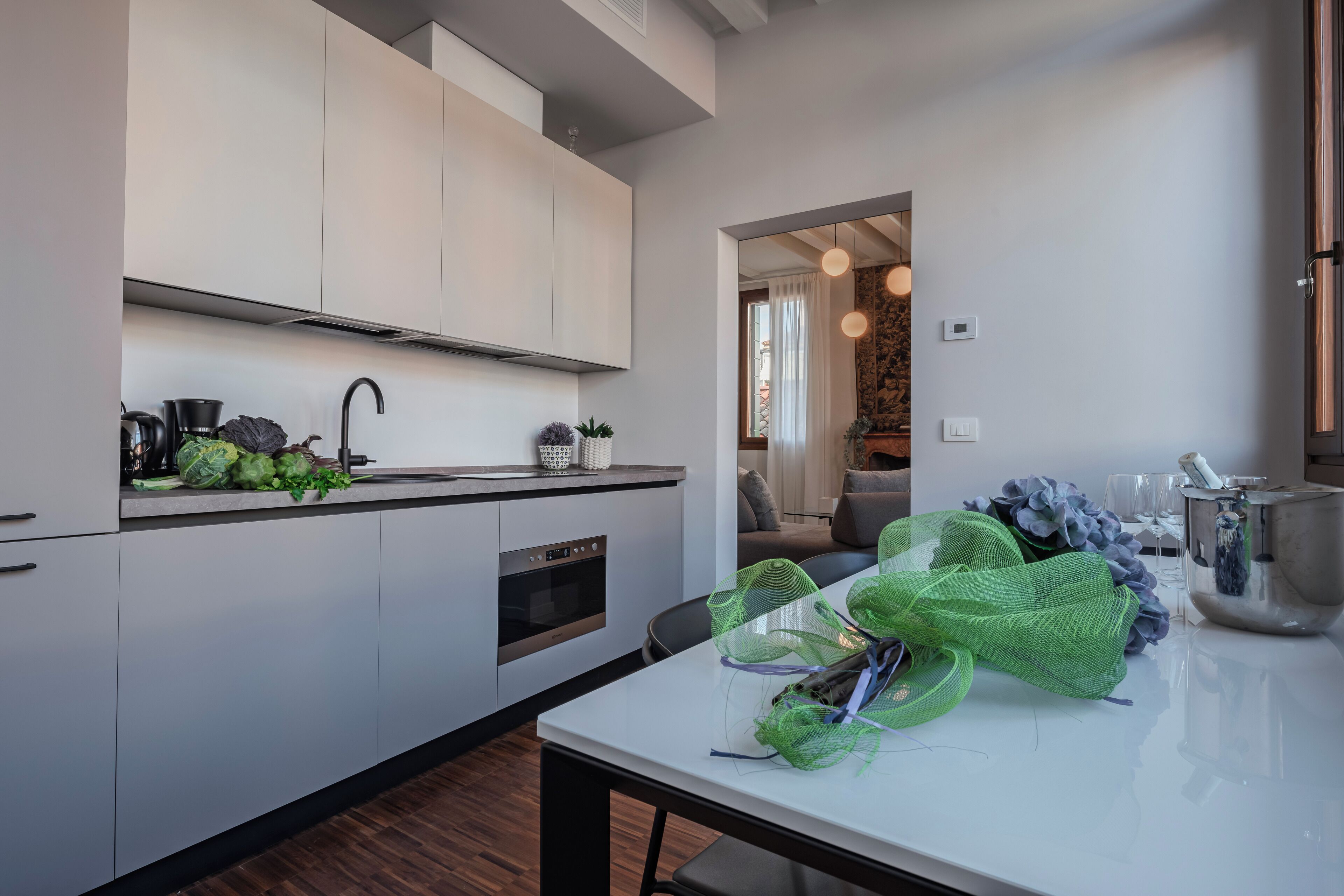 A modern kitchen with white cabinets, a stainless steel oven, and a dining area with a white table and chairs.