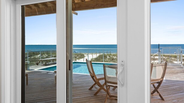 A wooden deck with a pool, chairs, and a view of the ocean. - Honeydew: Beautiful Beachfront Home with Private Pool and Pets Welcome! (Mexico Beach)