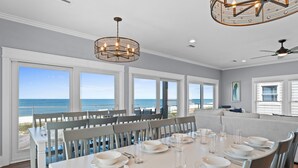 A dining room with a view of the ocean, large windows, and a chandelier. - Honeydew: Beautiful Beachfront Home with Private Pool and Pets Welcome! (Mexico Beach)