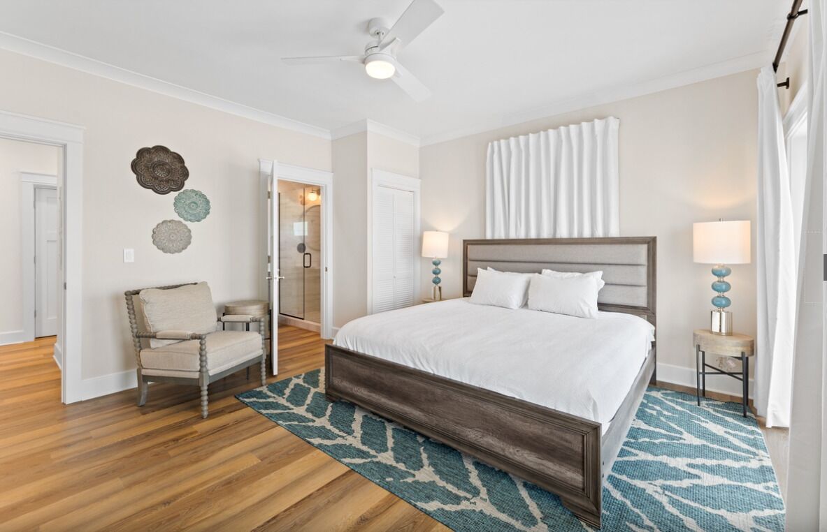 Une chambre à coucher avec un lit en bois, une chaise, une table de chevet et un ventilateur de plafond.