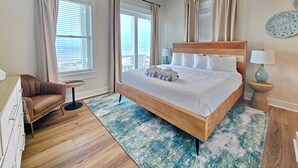 A hotel room with a large bed, a desk, a chair, a small table, and a ceiling fan. - Sugarcane: New Construction, Private Pool, 6 Bedrooms (Mexico Beach)