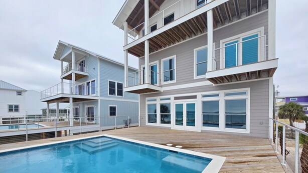 A modern multi-story building with a swimming pool and wooden deck. - Sugarcane: New Construction, Private Pool, 6 Bedrooms (Mexico Beach)