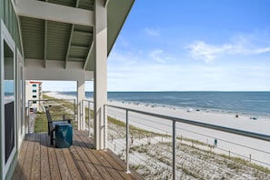 A wooden deck with a view of the beach and ocean.