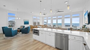 Una cocina moderna con armarios blancos, una isla grande y vistas al océano.