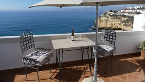 A terrace with a table and chairs, a bottle of wine, and a glass on the table. The terrace overlooks a cliff and the sea. - "Ocean View Terrace", The best sea view - directly on the beach of Carvoeiro (Carvoeiro)