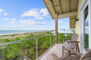 A balcony with a view of the beach and ocean, featuring a wooden deck, two Adirondack chairs, and a railing. - Suncastle: Beachfront South Cape, Private Pool, Pet-Friendly, Sleeps 24! (Cape San Blas)
