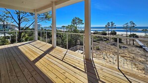 Eine Holzterrasse mit Blick auf Strand und Meer.